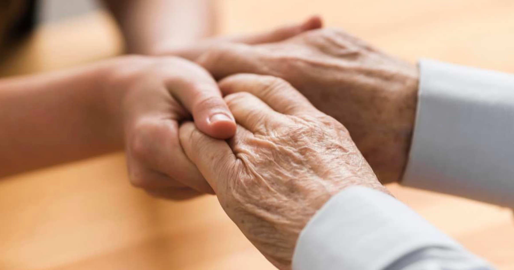 Deux personnes se tiennent les mains, une personne âgée et une plus jeune